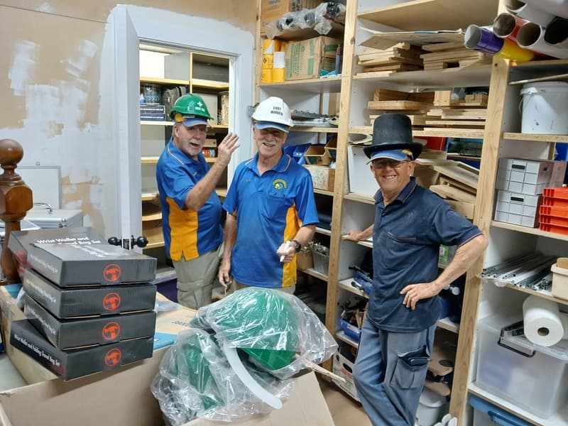 Three men smiling together inside the Shed workshop